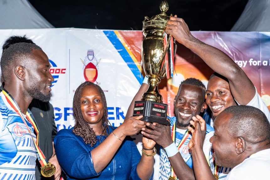 Aminah-Bukenya-Ag-Head-of-Corporate-Affairs-Department-shares-a-light-moment-with-Buhanguzi-County-team-who-are-the-winners-of-the-2024-Amasaza-Cup-Tournament-860x573